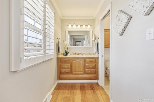 bathroom featuring visible vents, toilet, wood finished floors, crown molding, and vanity