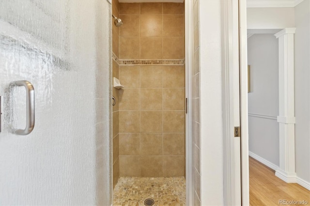 bathroom featuring wood finished floors, a stall shower, and ornamental molding