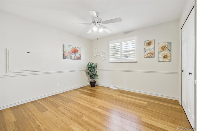 spare room featuring light wood finished floors, visible vents, baseboards, and a ceiling fan