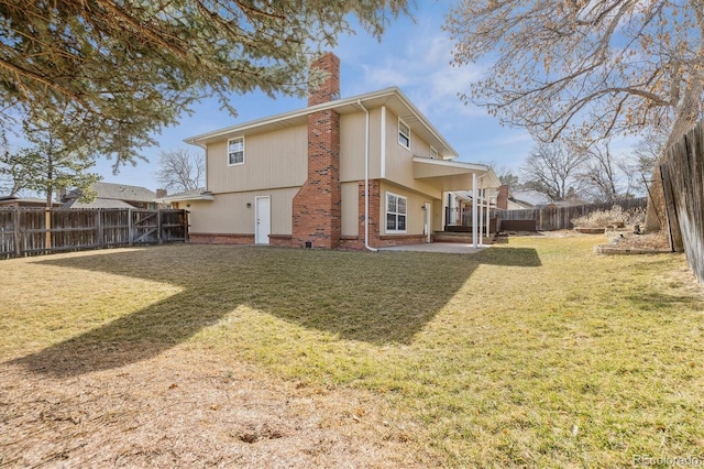 rear view of house featuring a patio, a lawn, a fenced backyard, and a chimney