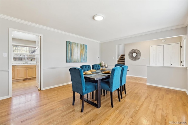 dining area featuring light wood-type flooring, crown molding, and baseboards