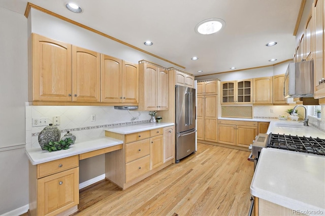 kitchen featuring light brown cabinets, a sink, backsplash, appliances with stainless steel finishes, and light wood finished floors