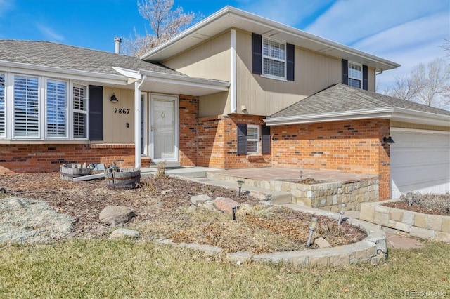 split level home with an attached garage, brick siding, and roof with shingles