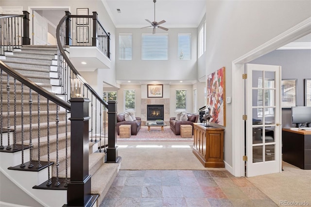 22419 Springflower Dr, Golden, CO 80401 - carpeted entryway featuring ornamental molding, a fireplace, a ceiling fan, stairs, and stone finish flooring