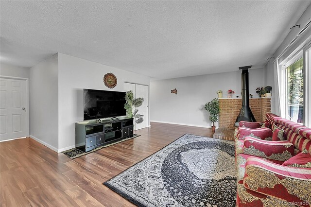 living room featuring a textured ceiling, hardwood / wood-style floors, and a wood stove