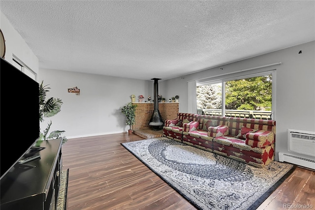 living room with a textured ceiling, dark hardwood / wood-style floors, baseboard heating, and a wood stove