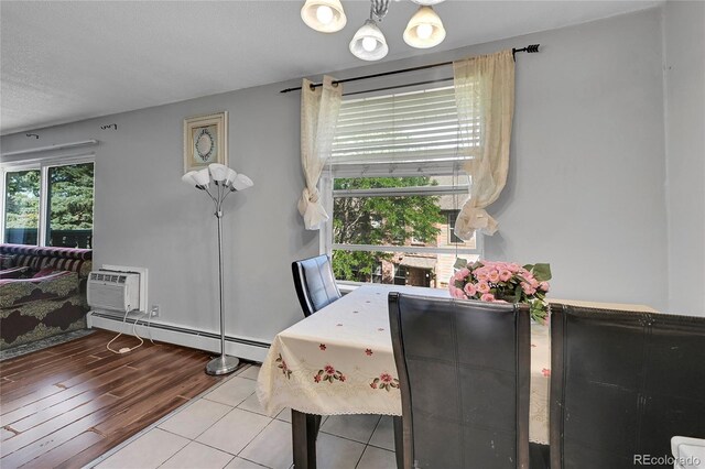 tiled dining room featuring a baseboard radiator, a chandelier, and a wall mounted AC