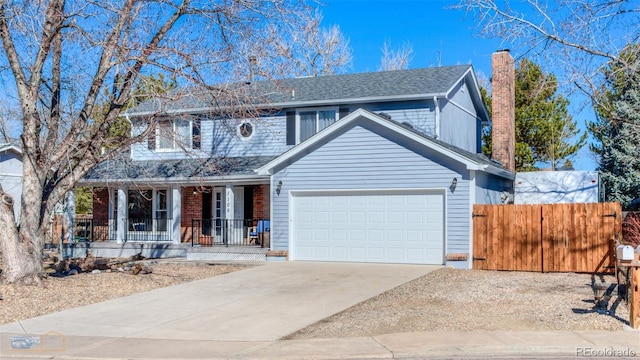 traditional home with a chimney, a porch, an attached garage, fence, and driveway