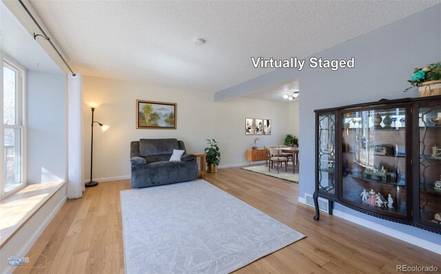 interior space with a textured ceiling, wood finished floors, and baseboards