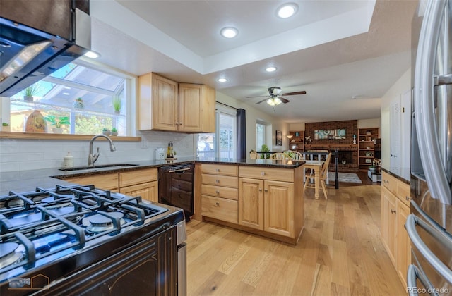 kitchen featuring light wood-style flooring, light brown cabinets, a sink, a peninsula, and black appliances