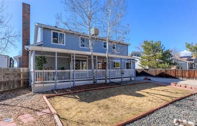 back of property with a fenced backyard and a chimney