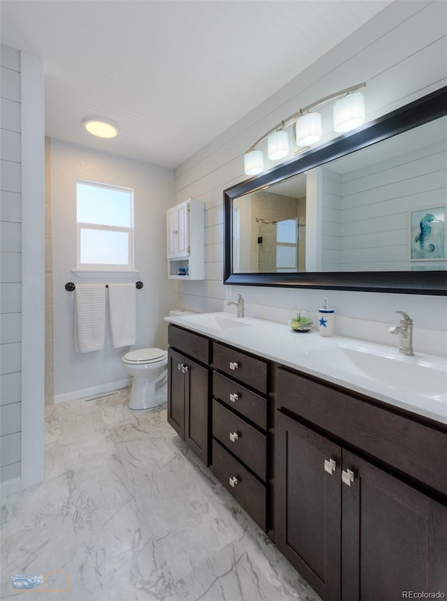 full bathroom featuring marble finish floor, a shower with door, a sink, and double vanity