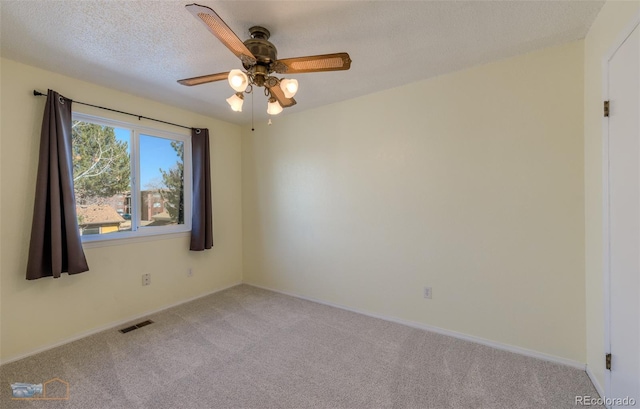 carpeted empty room featuring baseboards, ceiling fan, visible vents, and a textured ceiling