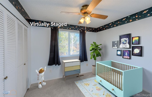 bedroom featuring a textured ceiling, carpet floors, a ceiling fan, a closet, and a nursery area