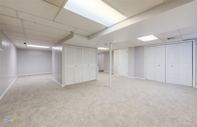 finished basement with carpet floors, a paneled ceiling, and baseboards