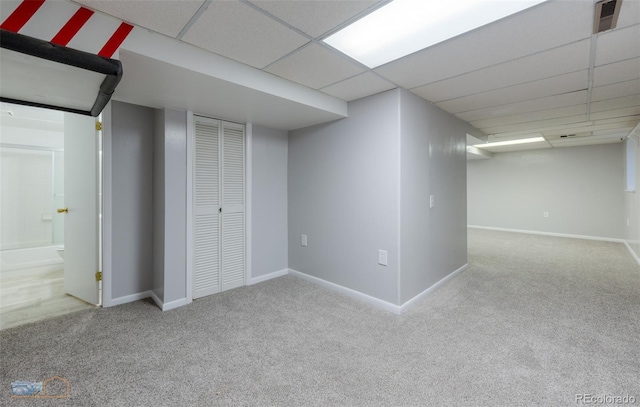 finished below grade area featuring carpet floors, a drop ceiling, and baseboards