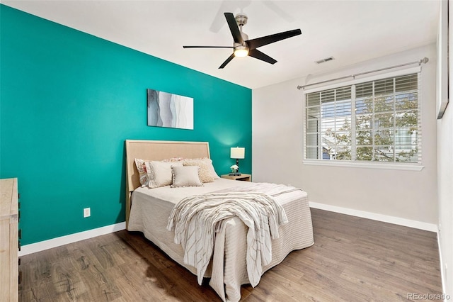 bedroom featuring baseboards, ceiling fan, wood finished floors, and visible vents