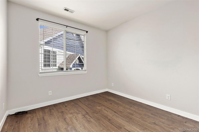 empty room with baseboards, wood finished floors, and visible vents