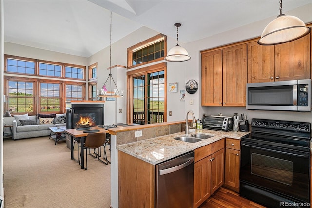 8305 Northstar Unit 8-305, Granby, CO 80446 - kitchen featuring appliances with stainless steel finishes, a sink, a peninsula, hanging light fixtures, and a glass covered fireplace