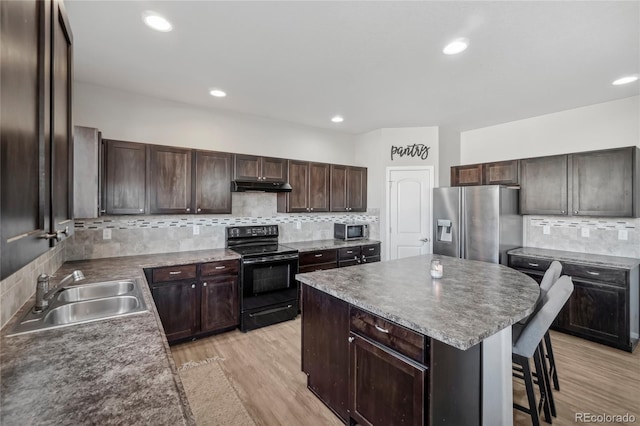 kitchen featuring decorative backsplash, stainless steel appliances, sink, light hardwood / wood-style floors, and a kitchen island