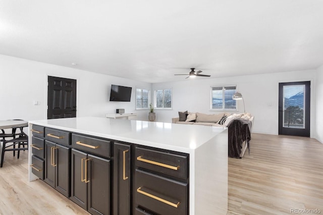 kitchen featuring open floor plan, light countertops, ceiling fan, and light wood-style flooring