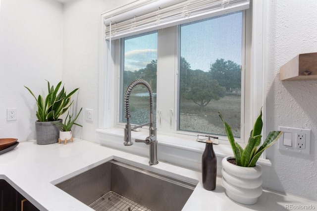 interior details featuring a textured wall, a sink, and light countertops