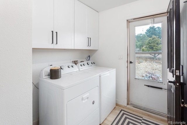 clothes washing area with light wood-type flooring, cabinet space, and separate washer and dryer