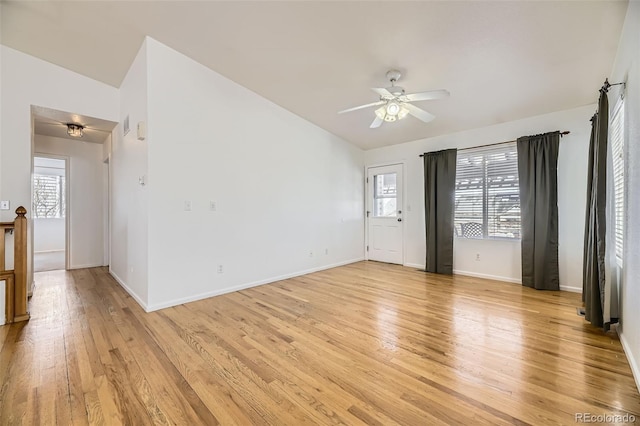 empty room with lofted ceiling, light wood-style flooring, baseboards, and ceiling fan