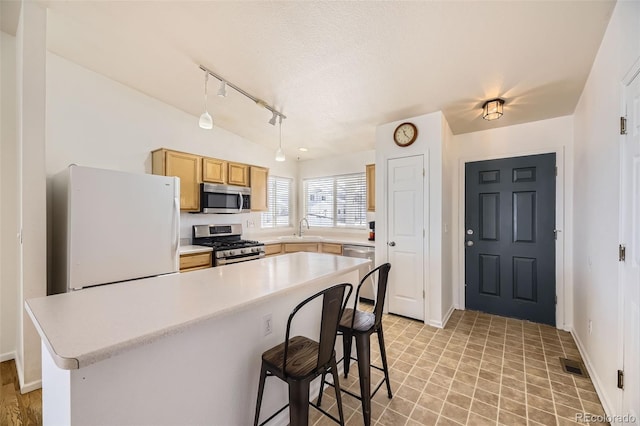 kitchen featuring a textured ceiling, stainless steel appliances, a sink, hanging light fixtures, and light countertops