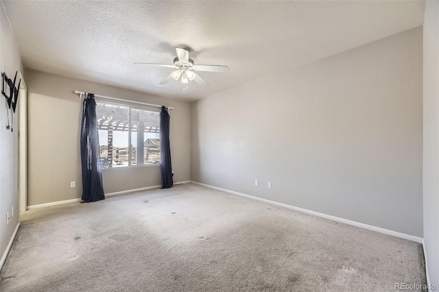 empty room featuring light carpet, ceiling fan, baseboards, and a textured ceiling