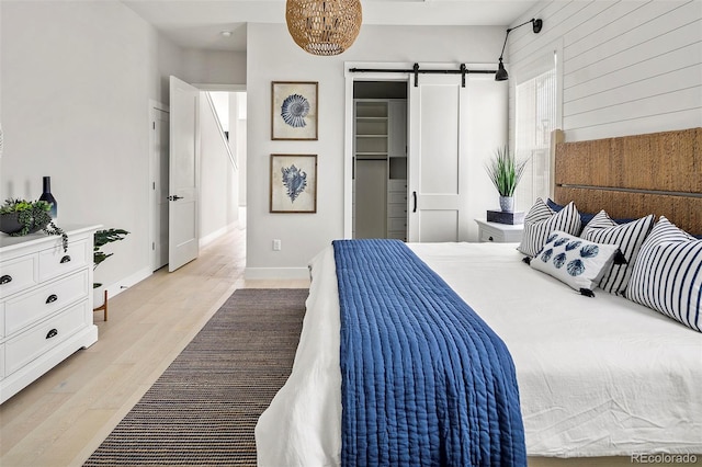 bedroom featuring a barn door and light wood-type flooring