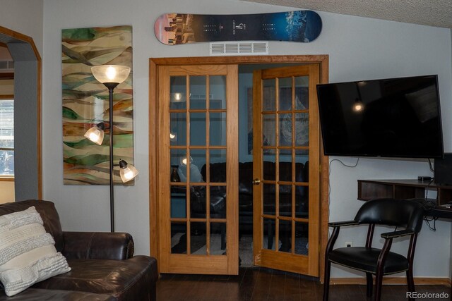 interior space with a textured ceiling, dark wood-type flooring, and french doors