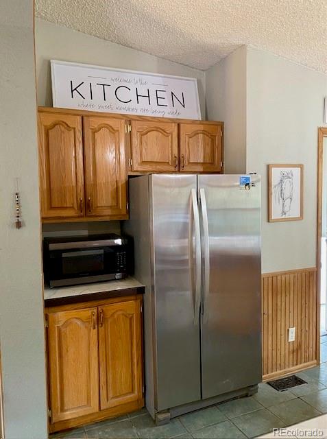 kitchen with a textured ceiling, tile patterned flooring, lofted ceiling, and stainless steel appliances