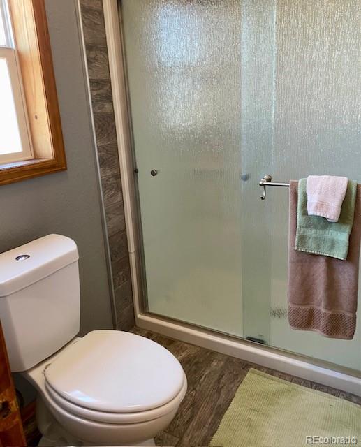 bathroom featuring hardwood / wood-style flooring, toilet, and an enclosed shower