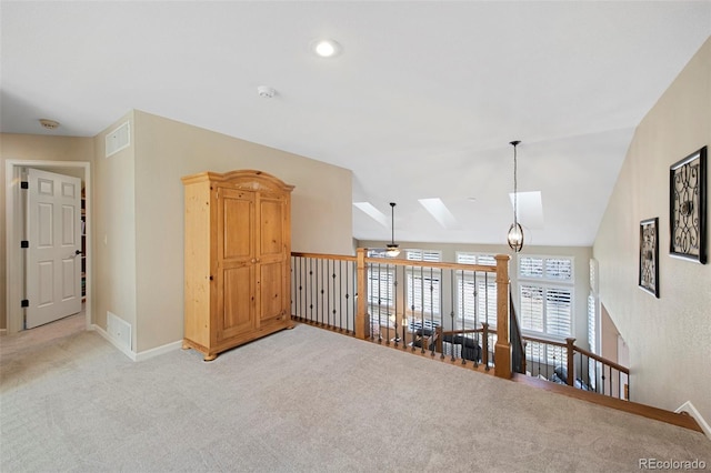 empty room featuring ceiling fan, light colored carpet, and lofted ceiling with skylight