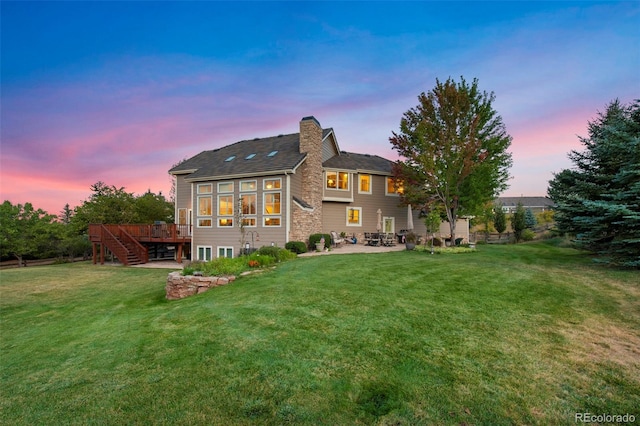 back house at dusk with a yard and a wooden deck