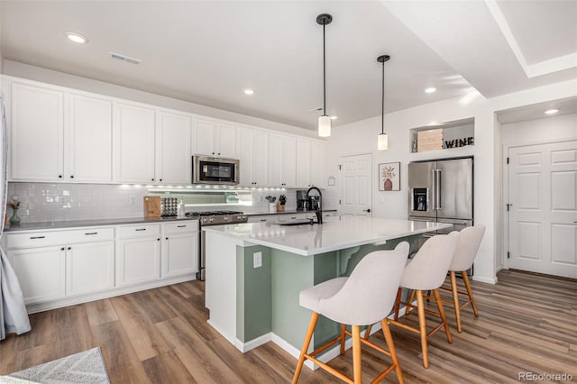 4104 N Picadilly Ct, Aurora, CO 80019 - kitchen with stainless steel appliances, decorative backsplash, light wood finished floors, white cabinetry, and recessed lighting