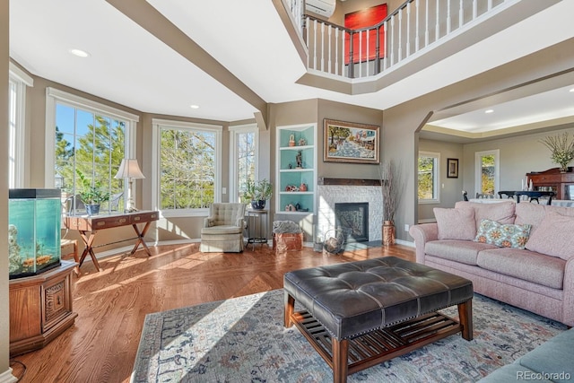 living area featuring arched walkways, recessed lighting, a fireplace, parquet flooring, and baseboards