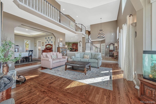 living room featuring stairs, a tray ceiling, a towering ceiling, and wood finished floors