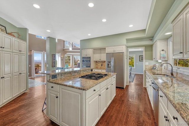 kitchen with stainless steel appliances, dark wood-type flooring, a kitchen island, a sink, and backsplash