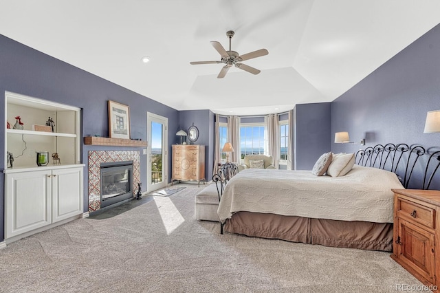 carpeted bedroom with recessed lighting, a tiled fireplace, vaulted ceiling, ceiling fan, and access to outside