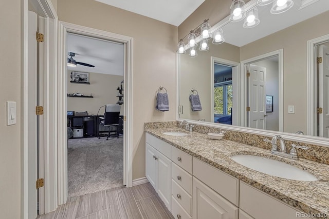 full bath with double vanity, baseboards, a ceiling fan, and a sink