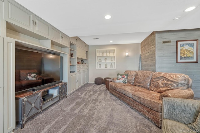 carpeted living area with built in shelves, wooden walls, and recessed lighting