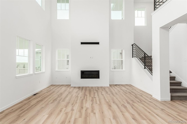 1826 Hickory Ave, Erie, CO 80516 - unfurnished living room with a high ceiling, wood finished floors, stairway, and a glass covered fireplace