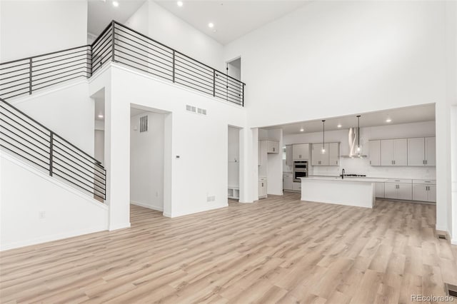 1826 Hickory Ave, Erie, CO 80516 - unfurnished living room with a towering ceiling, light wood finished floors, stairway, and recessed lighting