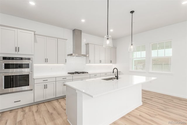 1826 Hickory Ave, Erie, CO 80516 - kitchen with wall chimney range hood, stainless steel appliances, light wood-type flooring, tasteful backsplash, and light countertops