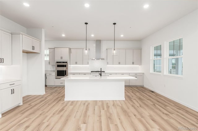 1826 Hickory Ave, Erie, CO 80516 - kitchen with wall chimney range hood, light countertops, backsplash, light wood-type flooring, and recessed lighting