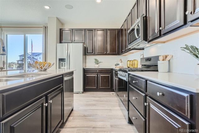 kitchen featuring dark brown cabinetry, appliances with stainless steel finishes, sink, and light hardwood / wood-style floors