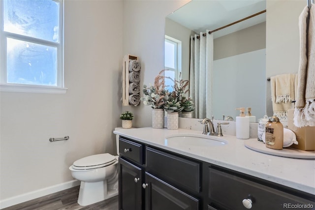 bathroom featuring hardwood / wood-style flooring, vanity, a wealth of natural light, and toilet