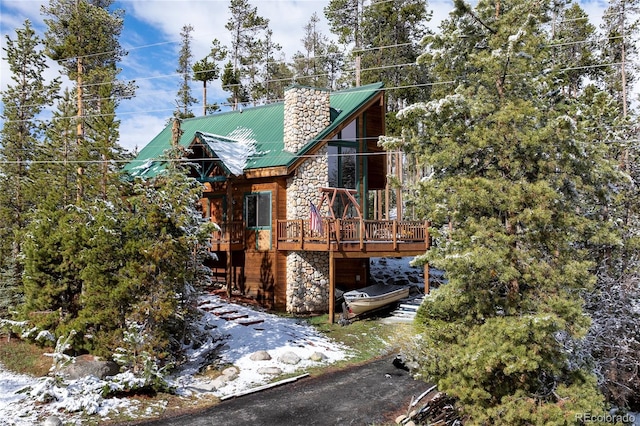 507 Gcr 4980, Grand Lake, CO 80447 - view of front facade featuring stone siding, a chimney, a wooden deck, and metal roof